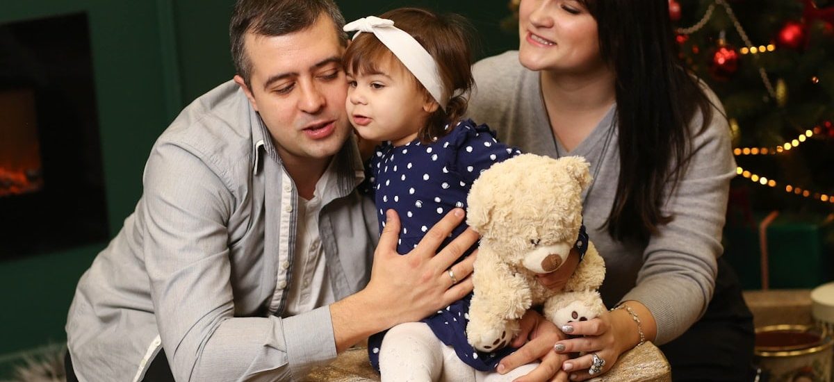 a man, woman and child sitting in front of a christmas tree