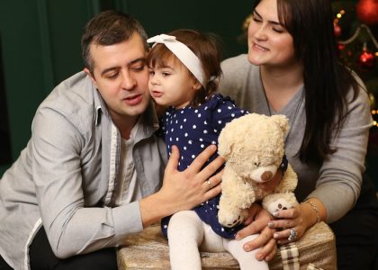 a man, woman and child sitting in front of a christmas tree